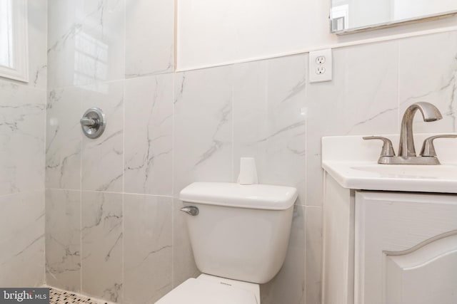 bathroom featuring toilet, tile walls, tiled shower, and vanity