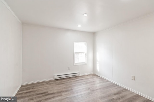 spare room with ornamental molding, baseboards, wood finished floors, and baseboard heating