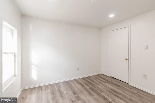 empty room featuring ornamental molding, baseboards, and light wood-type flooring