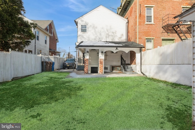 back of house featuring a fenced backyard and a lawn