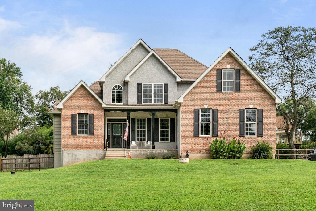 rear view of house with fence, a porch, and a yard