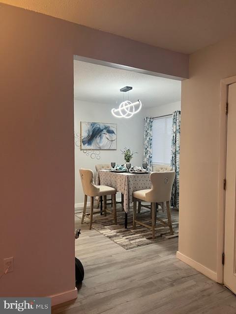 dining room with wood finished floors, a notable chandelier, and baseboards