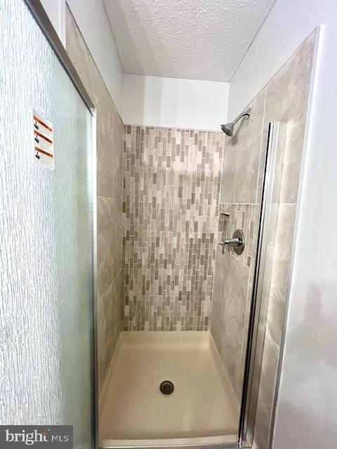 full bathroom featuring a textured ceiling and a stall shower