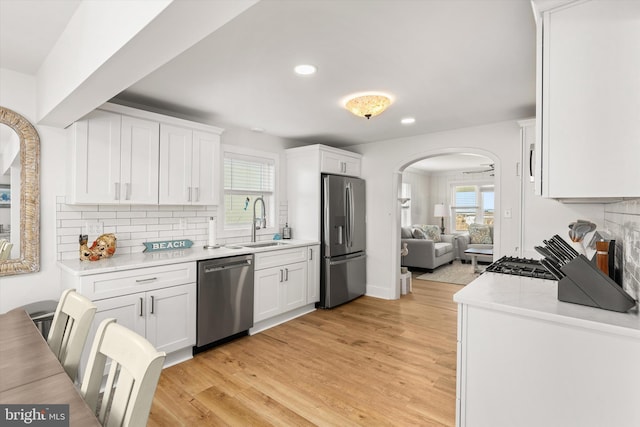 12353 Meadow Dr, Berlin, MD 21811 - kitchen with a sink, white cabinets, arched walkways, and stainless steel appliances