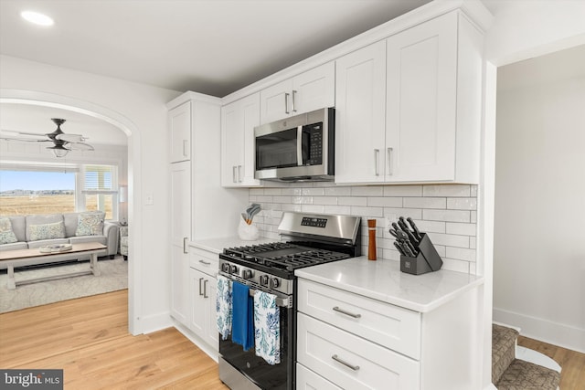 12353 Meadow Dr, Berlin, MD 21811 - kitchen featuring backsplash, white cabinets, ceiling fan, light wood finished floors, and appliances with stainless steel finishes