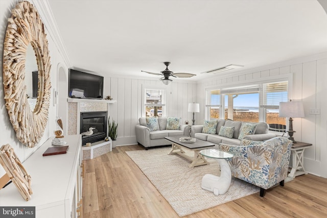 12353 Meadow Dr, Berlin, MD 21811 - living area featuring a decorative wall, ornamental molding, ceiling fan, light wood-style floors, and a tile fireplace