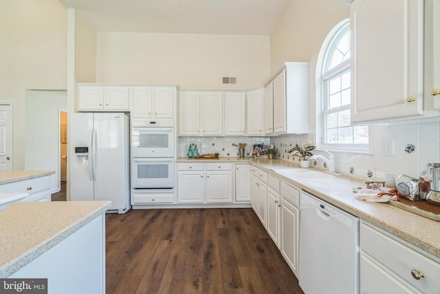 kitchen with visible vents, white appliances, backsplash, and a sink