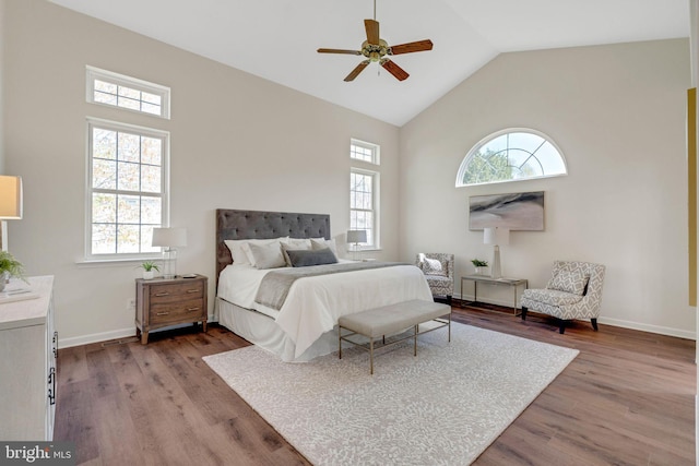 bedroom with wood finished floors, ceiling fan, high vaulted ceiling, and baseboards