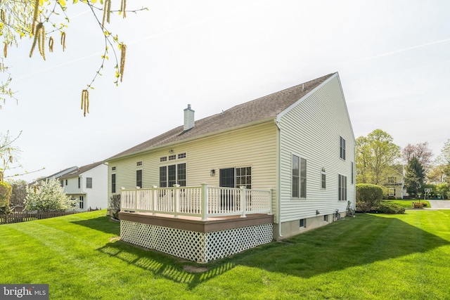 back of property with a chimney, a yard, and a wooden deck