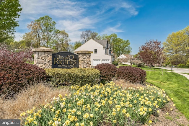 community / neighborhood sign featuring a yard and a garage