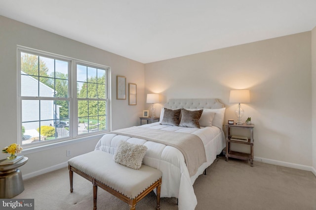 bedroom with light colored carpet and baseboards
