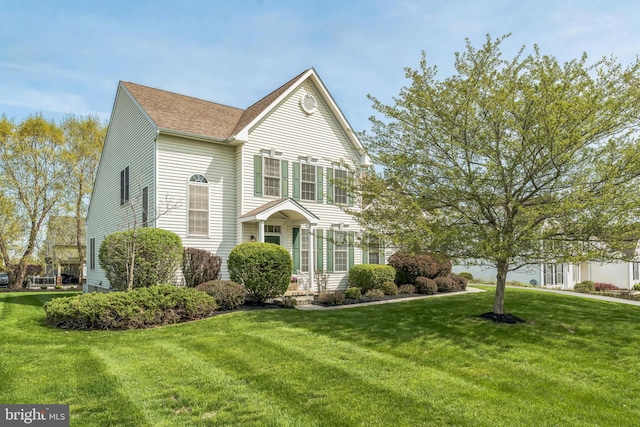traditional-style house with a front yard and a shingled roof