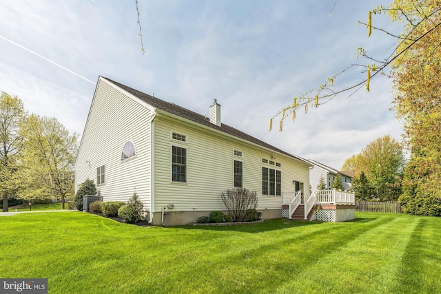 back of house featuring a lawn, a chimney, and a wooden deck