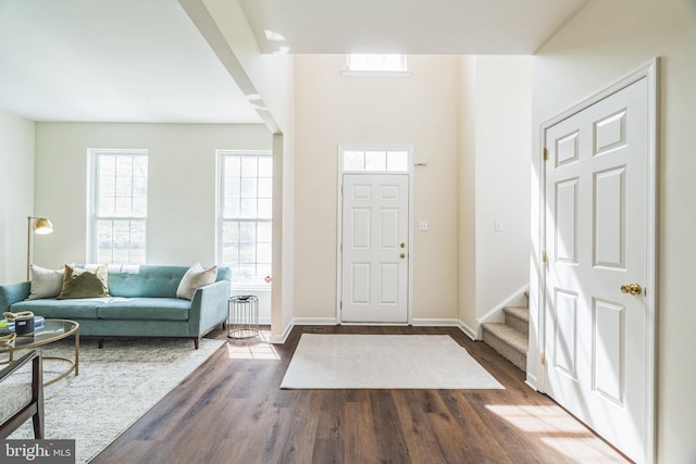 foyer entrance featuring baseboards, stairway, and wood finished floors