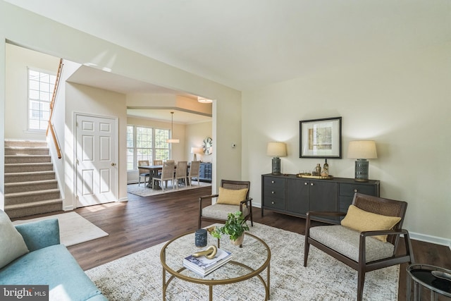 living area with stairway, wood finished floors, and baseboards