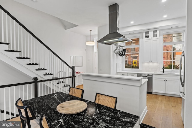 929 S 2nd St, Philadelphia, PA 19147 - kitchen with island exhaust hood, stainless steel dishwasher, a sink, light wood-style floors, and white cabinets