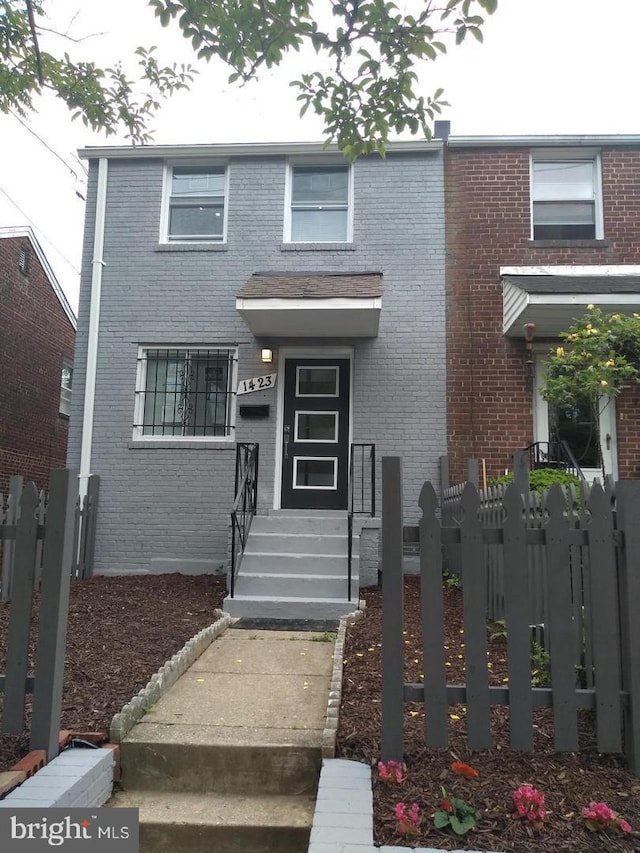 view of front of property featuring fence and brick siding