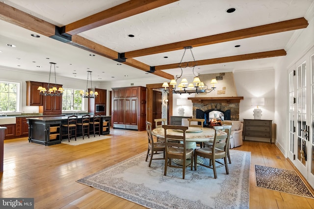 dining space featuring an inviting chandelier, a fireplace, light wood-style flooring, recessed lighting, and beamed ceiling