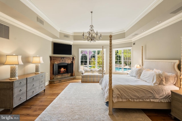 bedroom featuring visible vents, a raised ceiling, a notable chandelier, ornamental molding, and dark wood-type flooring
