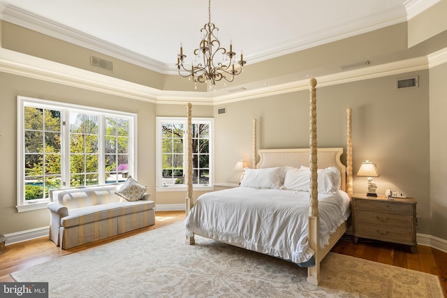 bedroom featuring multiple windows, a notable chandelier, wood finished floors, and visible vents
