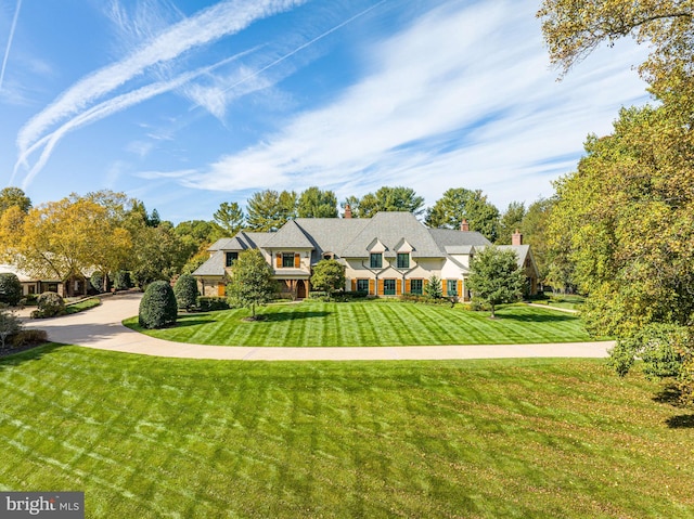 tudor home featuring a chimney and a front lawn