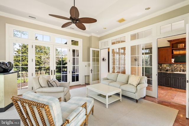 living area with visible vents, ornamental molding, ceiling fan, and a healthy amount of sunlight