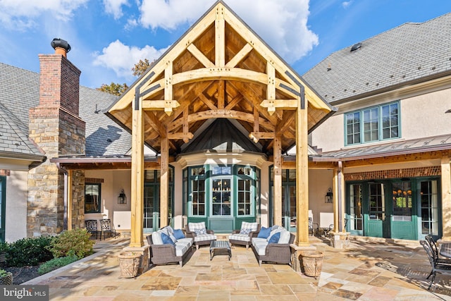 rear view of property with stucco siding, outdoor lounge area, a chimney, a standing seam roof, and a patio