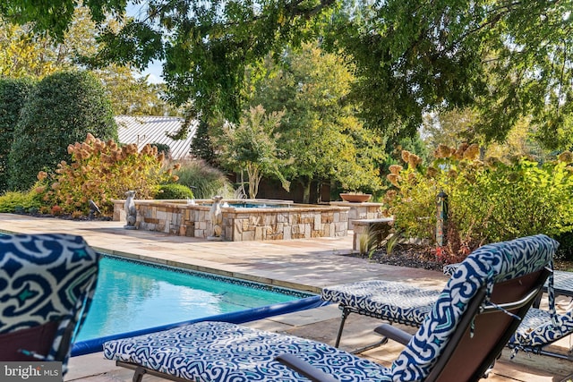 pool featuring a hot tub and a patio