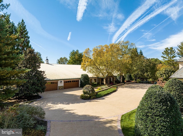 view of front of house with driveway, a chimney, and a garage