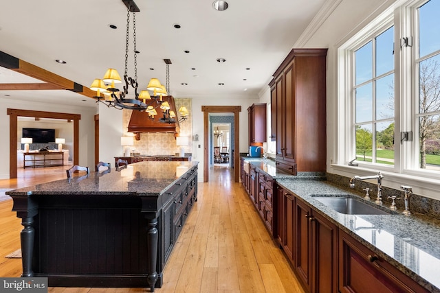 kitchen featuring an inviting chandelier, a large island, a sink, dark stone countertops, and decorative light fixtures