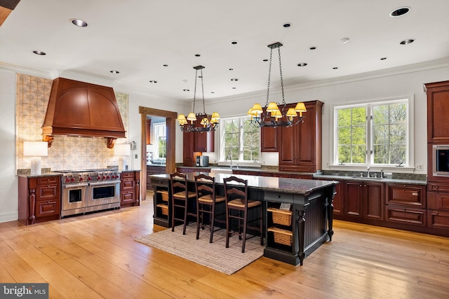 kitchen featuring a breakfast bar area, a kitchen island, range with two ovens, custom exhaust hood, and a chandelier