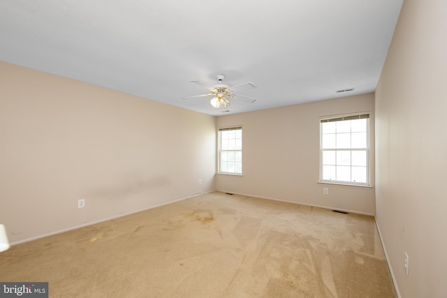 unfurnished room with baseboards, visible vents, ceiling fan, and light colored carpet