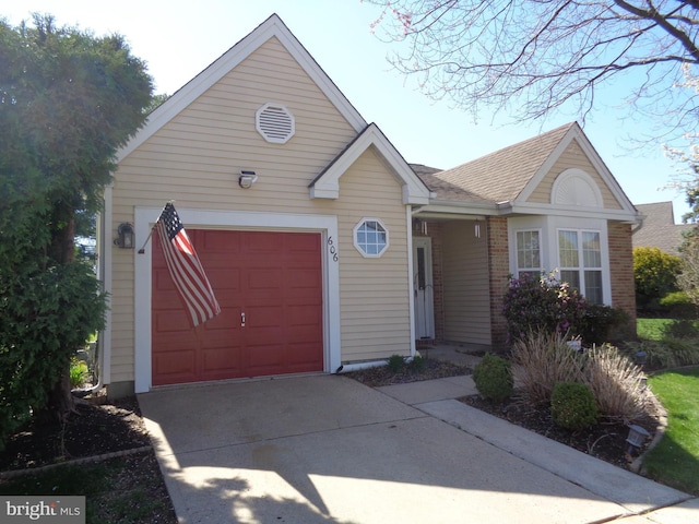 ranch-style home featuring concrete driveway, a garage, a shingled roof, and brick siding