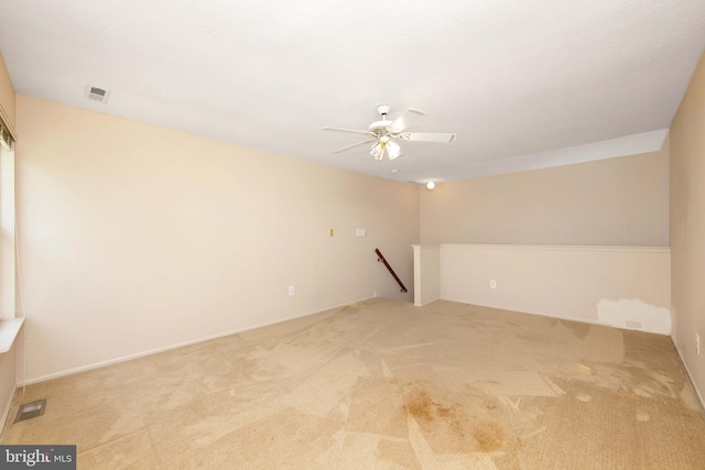 carpeted spare room with a ceiling fan and visible vents