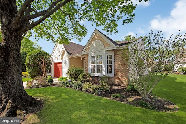 view of front of property with a front yard, an attached garage, and brick siding