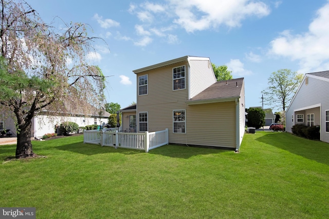 back of property with roof with shingles and a lawn