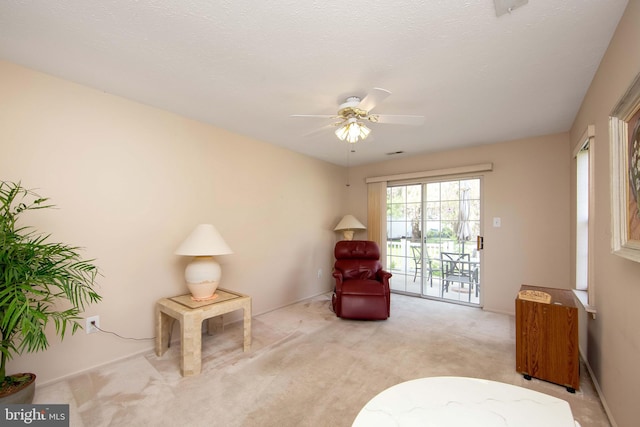 living area with a ceiling fan and carpet flooring