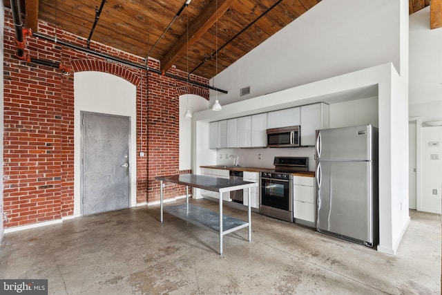 1714 Memphis St Unit 402, Philadelphia, PA 19125 - kitchen with wood ceiling, a high ceiling, brick wall, and stainless steel appliances