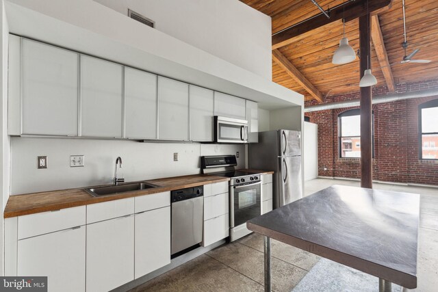 1714 Memphis St Unit 402, Philadelphia, PA 19125 - kitchen with brick wall, a sink, wood ceiling, beam ceiling, and stainless steel appliances