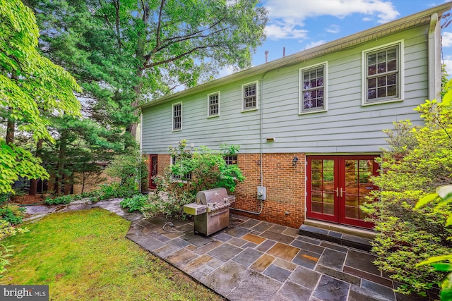 9127 Friars Rd, Bethesda, MD 20817 - rear view of house with french doors, a patio area, brick siding, and a yard