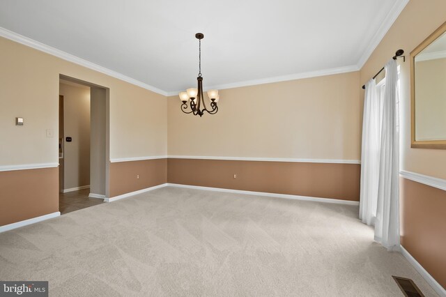 spare room featuring carpet flooring, a chandelier, visible vents, baseboards, and ornamental molding