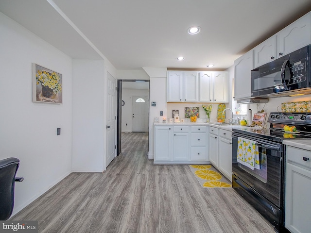 112 Jackson Ave, New Castle, DE 19720 - kitchen with recessed lighting, light wood-style floors, light countertops, black appliances, and white cabinetry