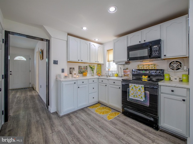 112 Jackson Ave, New Castle, DE 19720 - kitchen featuring black appliances, wood finished floors, and white cabinets