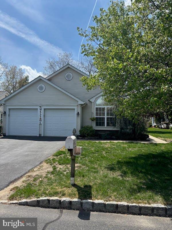 view of front of house featuring aphalt driveway, a front yard, and a garage