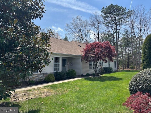 view of front facade featuring a shingled roof and a front yard