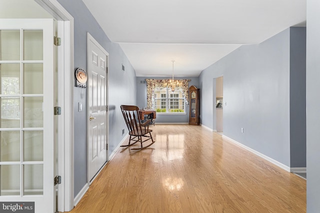 living area featuring baseboards, wood finished floors, and a notable chandelier