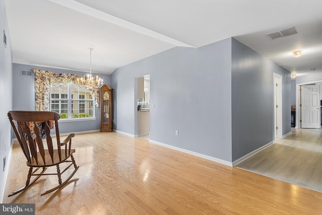 unfurnished room with baseboards, a chandelier, visible vents, and light wood-style flooring