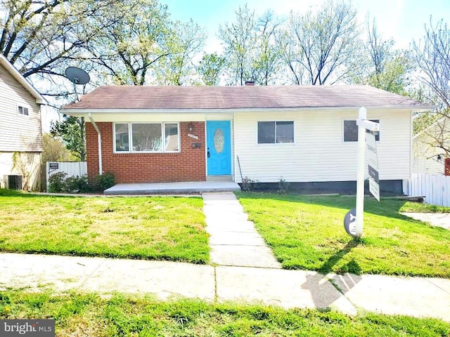 view of front of house featuring cooling unit, fence, a front lawn, and brick siding