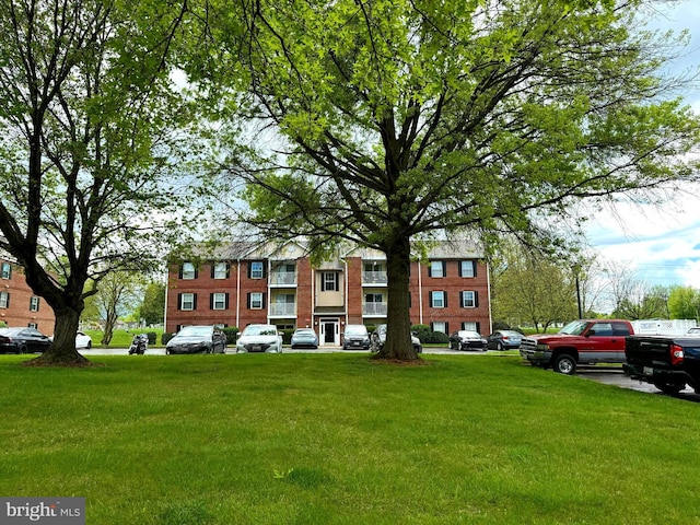 surrounding community with a lawn and uncovered parking