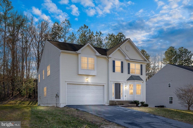 traditional home with an attached garage, aphalt driveway, and a front lawn
